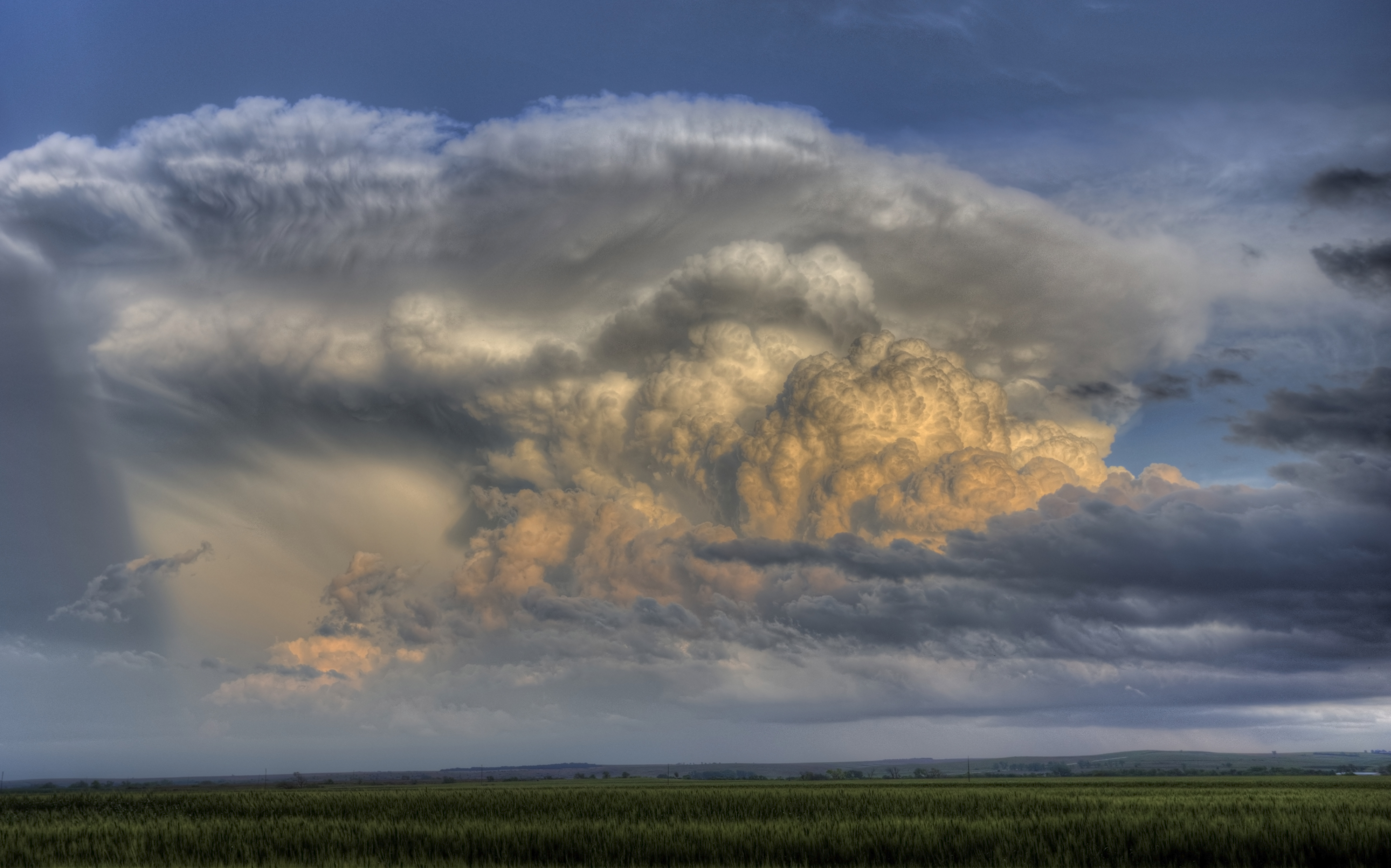 A sculpted thunderstorm cloud over open fields